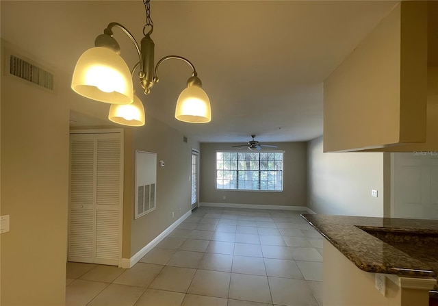 unfurnished dining area with light tile patterned floors and ceiling fan with notable chandelier