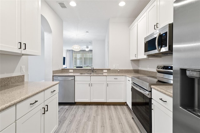 kitchen featuring appliances with stainless steel finishes, white cabinetry, sink, light stone counters, and light hardwood / wood-style flooring