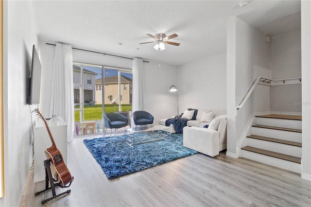 living room featuring ceiling fan, a textured ceiling, and light hardwood / wood-style flooring