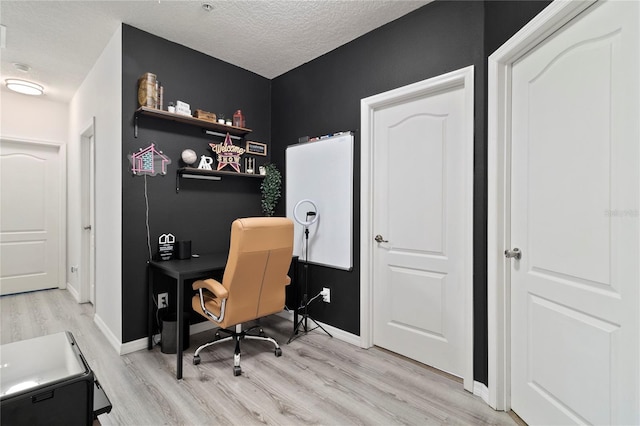 office area with light hardwood / wood-style floors and a textured ceiling