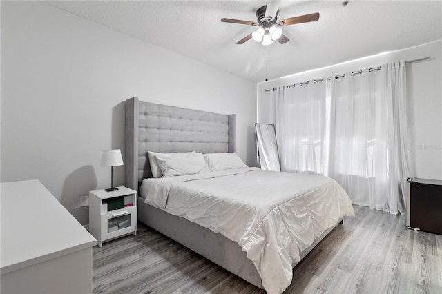 bedroom with ceiling fan, light hardwood / wood-style floors, and a textured ceiling