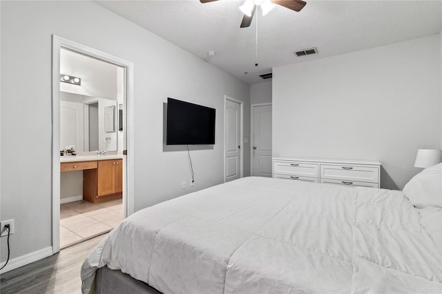 bedroom featuring ceiling fan, connected bathroom, a textured ceiling, and light hardwood / wood-style flooring