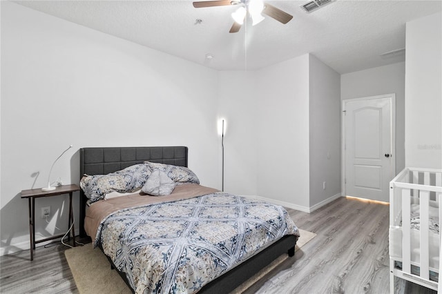 bedroom with ceiling fan, a textured ceiling, and light hardwood / wood-style flooring