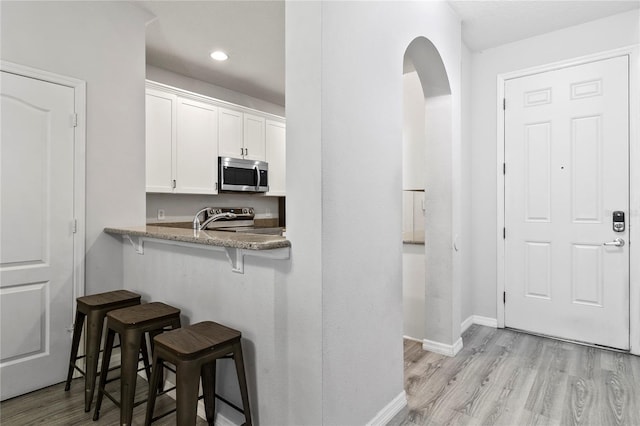 3257 Villa Strada Way, Orlando, FL 32835 - kitchen with white cabinets, light wood-style flooring, a breakfast bar area, and stainless steel appliances