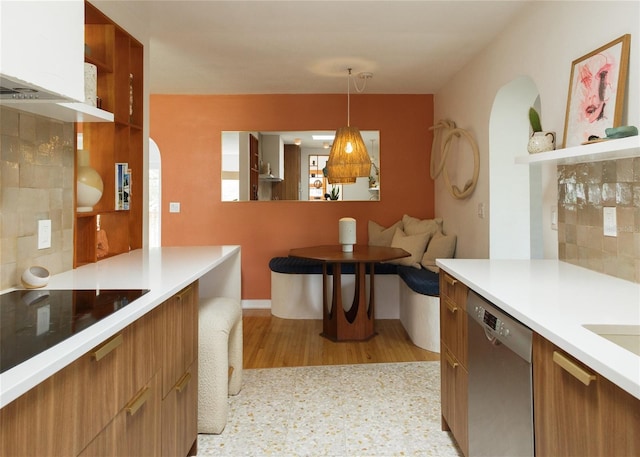 kitchen featuring tasteful backsplash, hanging light fixtures, black electric stovetop, stainless steel dishwasher, and light hardwood / wood-style floors