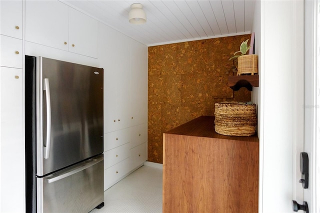 kitchen with white cabinetry, wood ceiling, and stainless steel fridge