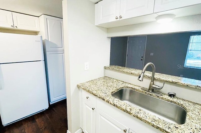 kitchen featuring white refrigerator, sink, light stone counters, and white cabinets