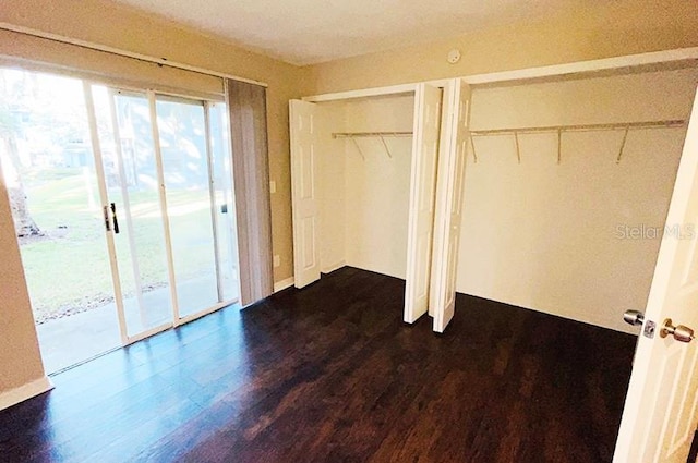 unfurnished bedroom featuring access to exterior, two closets, and dark hardwood / wood-style floors