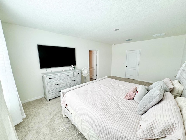 bedroom featuring light colored carpet and a textured ceiling