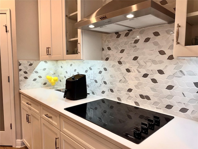 kitchen featuring black electric stovetop, decorative backsplash, and exhaust hood