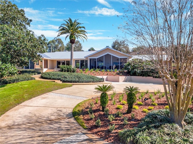 view of front of property featuring metal roof, a front lawn, a sunroom, and stucco siding