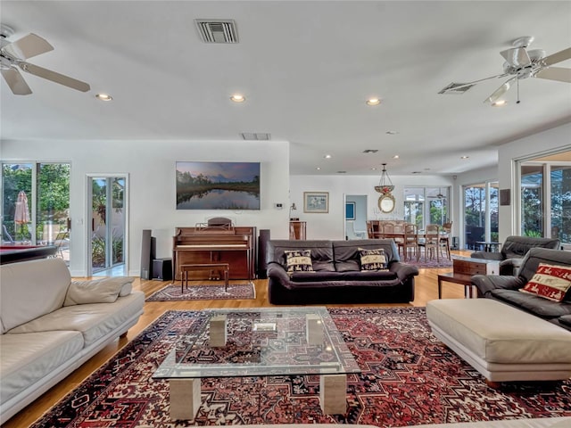 living room with light wood-type flooring, visible vents, and a wealth of natural light