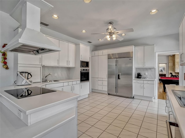 kitchen featuring decorative backsplash, built in appliances, island exhaust hood, light countertops, and a sink