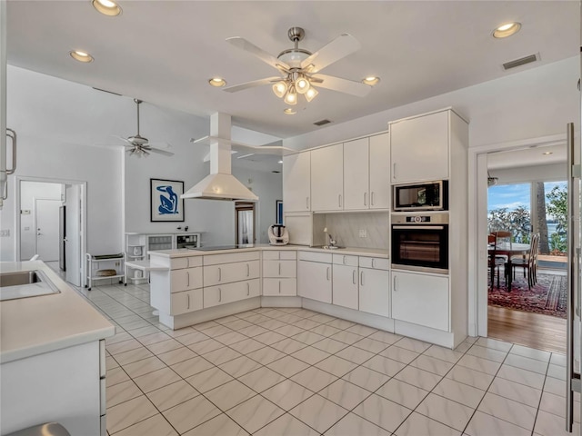 kitchen with light tile patterned floors, a peninsula, a sink, stainless steel oven, and built in microwave