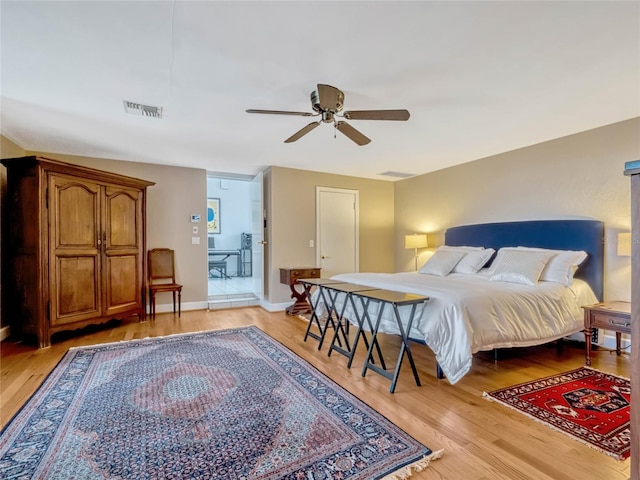 bedroom featuring light wood-style floors, baseboards, visible vents, and a ceiling fan