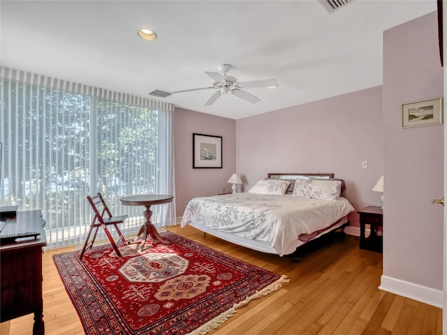 bedroom with a wall of windows, wood finished floors, visible vents, and baseboards