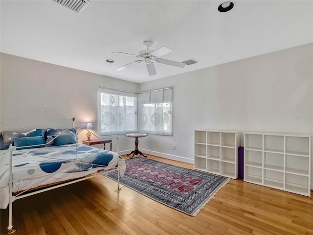 bedroom featuring wood-type flooring, visible vents, ceiling fan, and baseboards