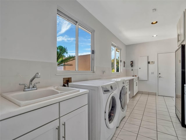 laundry area with light tile patterned floors, recessed lighting, separate washer and dryer, a sink, and cabinet space