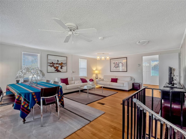 living room featuring a textured ceiling, wood finished floors, visible vents, and a ceiling fan