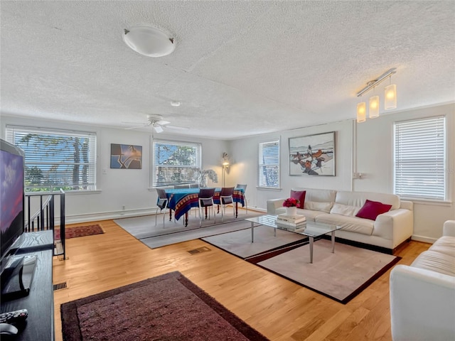 living room with baseboards, ceiling fan, wood finished floors, a textured ceiling, and track lighting