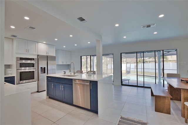 kitchen featuring sink, blue cabinetry, white cabinetry, plenty of natural light, and stainless steel appliances