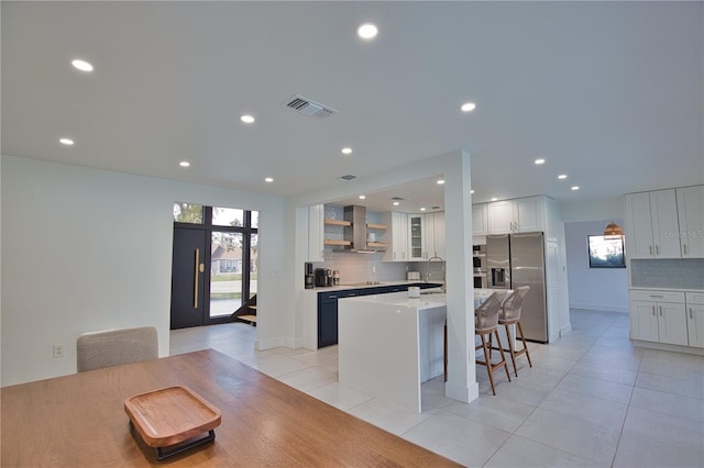 kitchen featuring a breakfast bar, stainless steel refrigerator with ice dispenser, white cabinets, a kitchen island, and wall chimney exhaust hood