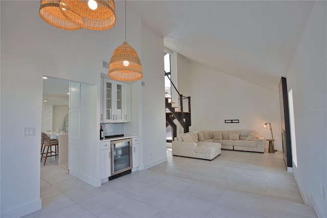 living room featuring light tile patterned floors, high vaulted ceiling, beverage cooler, and indoor bar