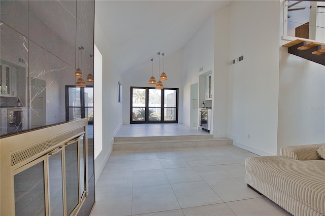 hall featuring high vaulted ceiling and light tile patterned flooring