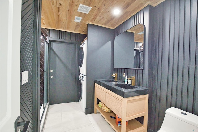 bathroom featuring wood ceiling, tile patterned flooring, vanity, stacked washer / drying machine, and toilet