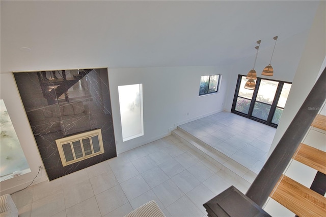 living room featuring vaulted ceiling, light tile patterned flooring, and a high end fireplace