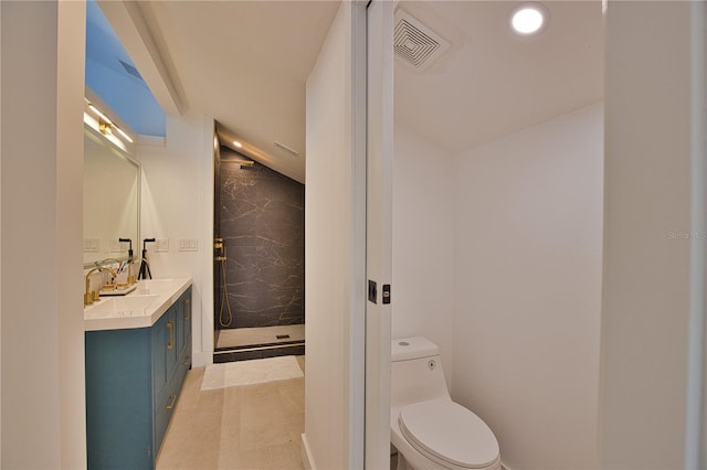 bathroom with tiled shower, vanity, and toilet