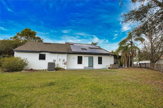 back of property featuring central air condition unit, a lawn, and solar panels