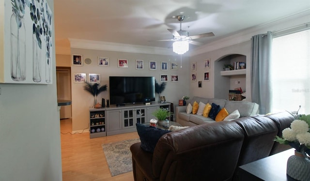 living room with built in shelves, ceiling fan, ornamental molding, and light hardwood / wood-style floors