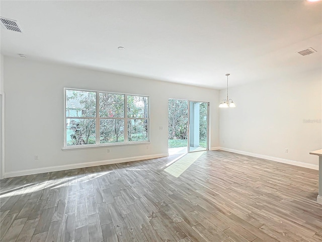 unfurnished room with light hardwood / wood-style floors and a chandelier
