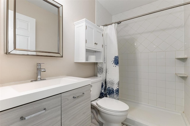 bathroom with tiled shower, vanity, and toilet