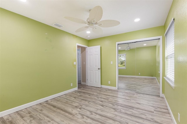 unfurnished room with a ceiling fan, wood finished floors, visible vents, and baseboards