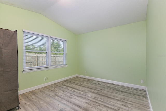 unfurnished room with lofted ceiling, wood finished floors, and baseboards