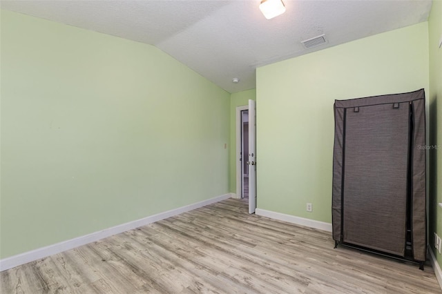 spare room with vaulted ceiling, wood finished floors, and baseboards