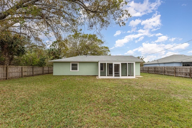 back of property featuring a lawn, a fenced backyard, a sunroom, and stucco siding