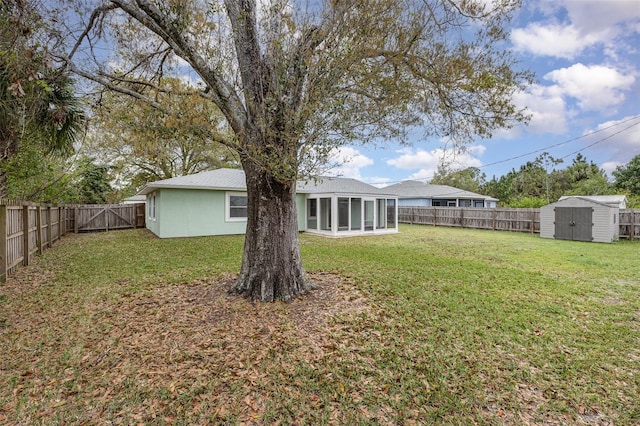 view of yard featuring a storage shed, a fenced backyard, a sunroom, and an outbuilding