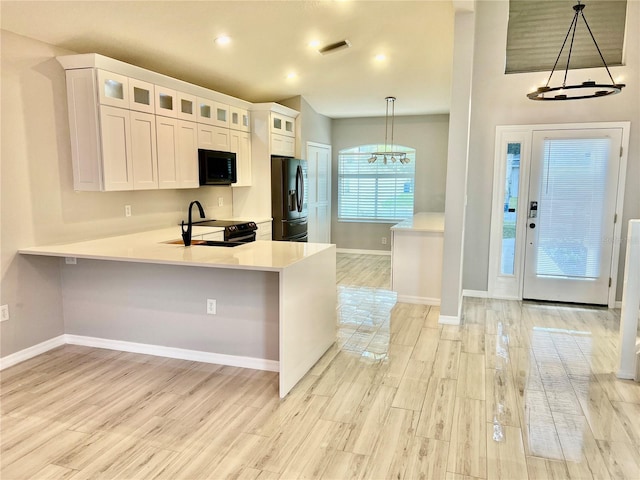 kitchen featuring decorative light fixtures, black appliances, white cabinetry, kitchen peninsula, and light wood-type flooring