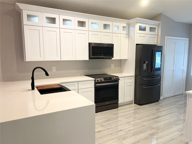 kitchen featuring sink, stainless steel appliances, white cabinets, and light wood-type flooring