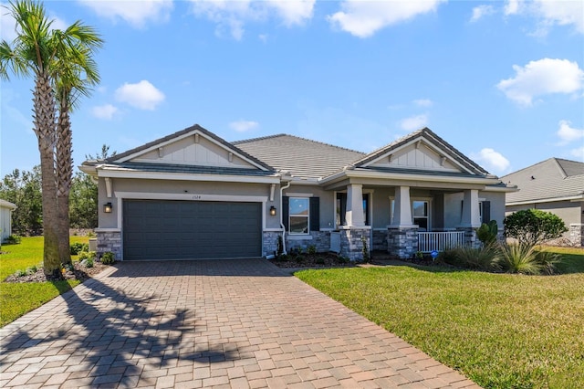 craftsman-style house featuring a garage, covered porch, and a front yard