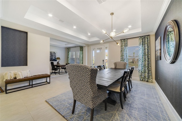 tiled dining room featuring a chandelier, ornamental molding, and a raised ceiling