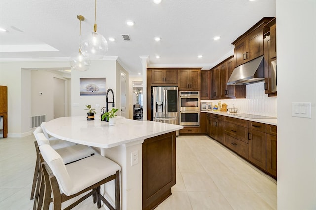 kitchen featuring appliances with stainless steel finishes, a breakfast bar, pendant lighting, sink, and a kitchen island with sink