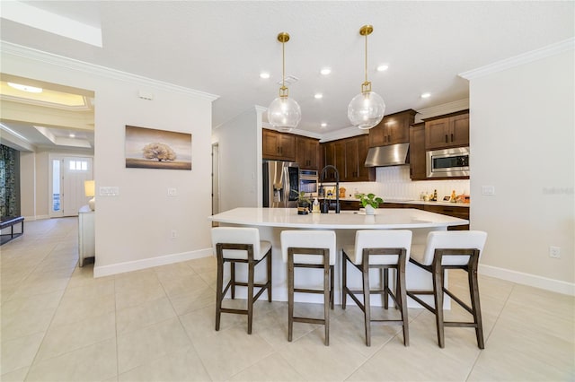 kitchen featuring tasteful backsplash, hanging light fixtures, an island with sink, and appliances with stainless steel finishes