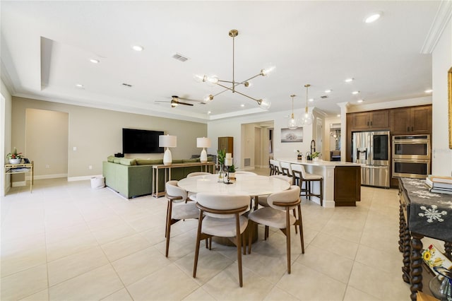 tiled dining space with ornamental molding, a tray ceiling, and ceiling fan with notable chandelier