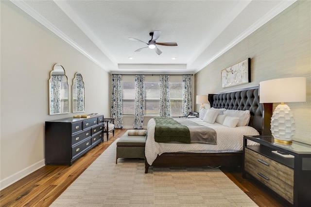 bedroom featuring hardwood / wood-style flooring, a textured ceiling, ceiling fan, and a tray ceiling