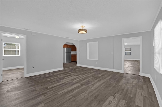 unfurnished living room with crown molding, a textured ceiling, and dark hardwood / wood-style flooring