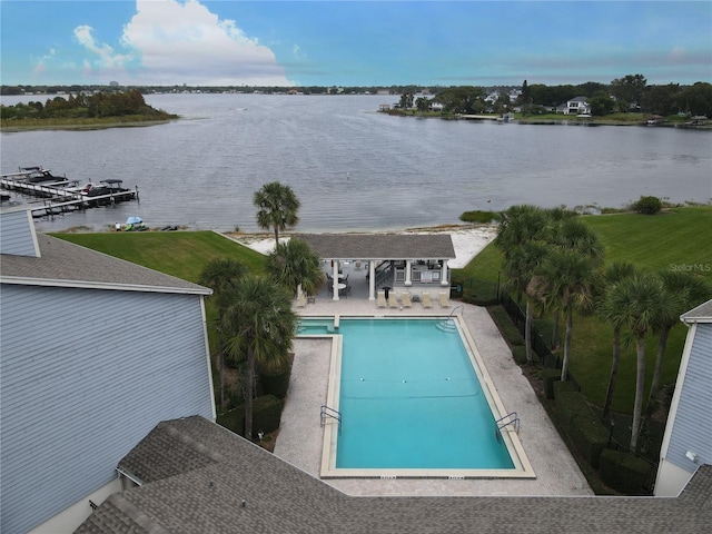 view of swimming pool featuring a patio, a water view, and an outbuilding